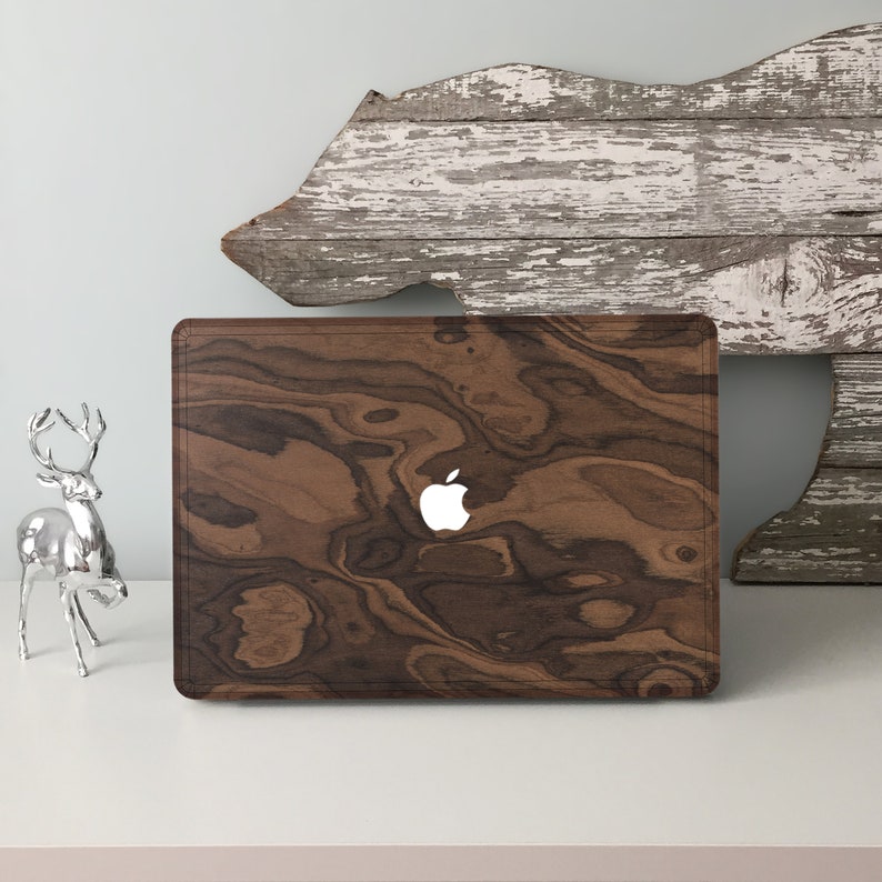 May include: A brown wood laptop case with a white Apple logo. The case has a wood grain pattern.