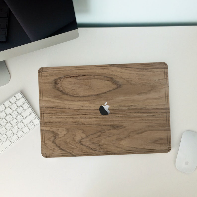 Puede incluir: Una piel para port&aacute;til de madera con un logotipo de Apple plateado. La piel es de color marr&oacute;n claro con un patr&oacute;n de madera.