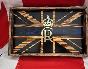 May include: A wooden tray with a burnt wood finish, featuring a black and gold Union Jack design with a blue stripe and a gold crown and "C III R" in the centre.