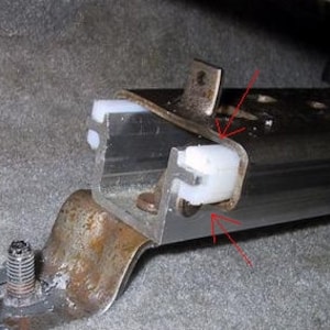 May include: Close-up of a silver metal track with two white plastic sliders. The sliders are located on the side of the track and are used to adjust the position of the track.