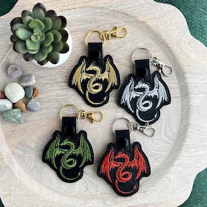 Llavero de dragón bordado: llavero o colgante para bolso con silueta de dragón alado, un regalo ideal para lectores de fantasía y amantes de los dragones.