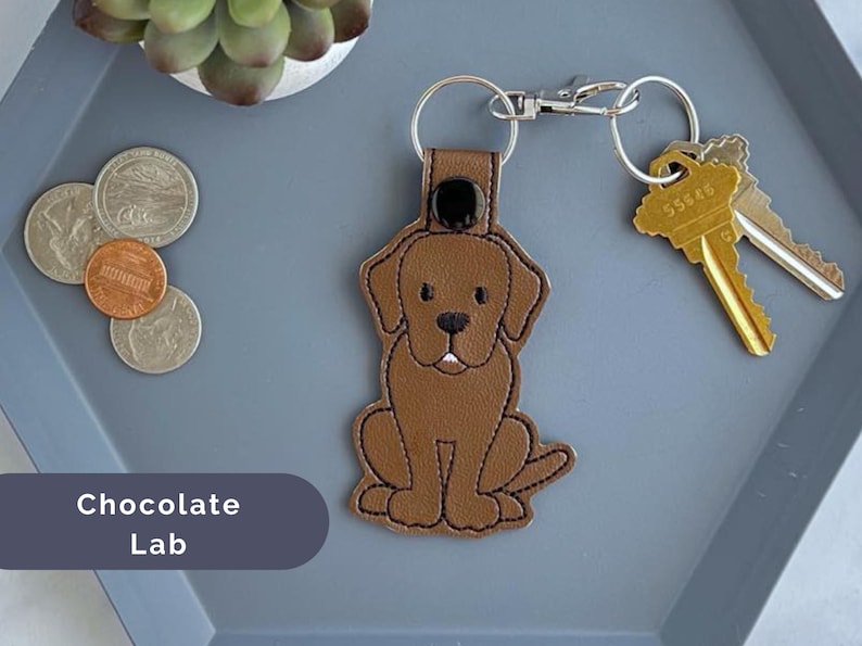 Puede incluir: Llavero de perro labrador chocolate con un dise&ntilde;o de cuero marr&oacute;n. El llavero tiene un anillo de metal plateado y un cierre de metal plateado.