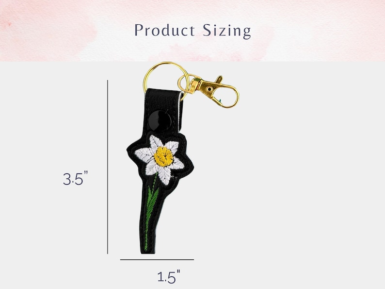 May include: Black leather keychain with a white embroidered flower and a gold key ring. The keychain measures 3.5 inches in length and 1.5 inches in width.