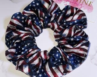Puede incluir: Una goma para el pelo con un estampado de la bandera estadounidense, con rayas rojas y blancas y estrellas blancas sobre un fondo azul. Este accesorio para el cabello está diseñado para añadir un toque patriótico a cualquier peinado. La goma para el pelo está hecha de tela suave.