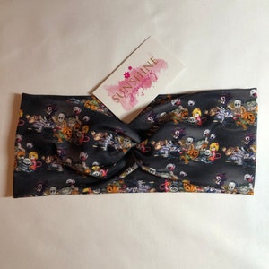 May include: A black headband with a twisted knot in the center. The headband is printed with a Halloween theme featuring various cartoon characters and pumpkins.