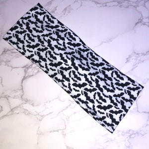 May include: Black and white headband with a bat pattern.