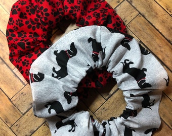 May include: Two fabric scrunchies, one red with black paw prints and one gray with black dachshund silhouettes.