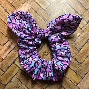 May include: Purple and pink fabric hair scrunchie with a mushroom print.