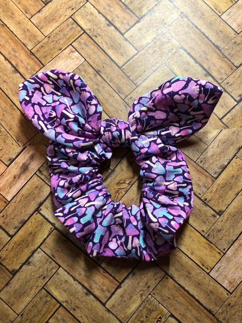 May include: Purple and pink fabric hair scrunchie with a mushroom print.