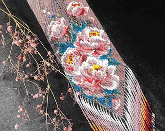 May include: A long, narrow beaded necklace featuring a floral pattern with pink, white, and blue flowers on a translucent background. The bottom section consists of long, multi-colored fringe strands in shades of white, pink, orange, and red.