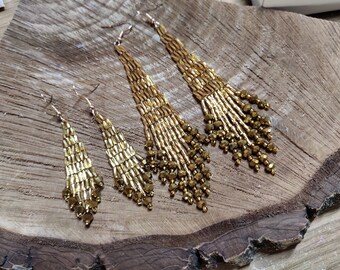 May include: Four pairs of gold beaded dangle earrings with varying lengths. The earrings are made with gold beads and have a teardrop shape.