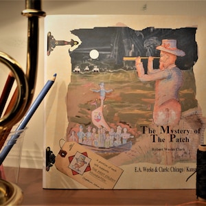 May include: The Mystery of The Patch book cover features a collage of illustrations. A man with a telescope looks out over a group of people in a boat. The book is by Robert Weeks Clark and published by E.A. Weeks & Clark: Chicago/Kansas.