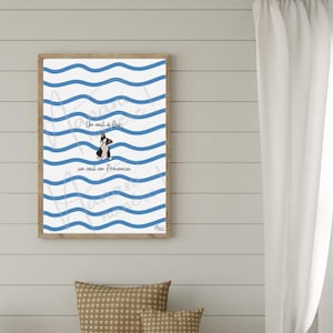 Peut inclure: Impression d'art encadrée avec une illustration de chien et le texte "Un oeil à Aix, un oeil en Provence". L'œuvre d'art a un fond blanc avec des lignes ondulées bleues et est dans un cadre en bois brun clair.
