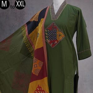 May include: Olive green kurta suit with a matching dupatta. The kurta features a geometric embroidered neckline and a diamond-shaped patch with colorful patterns. The dupatta has a patchwork design in yellow, red, black, and navy blue.