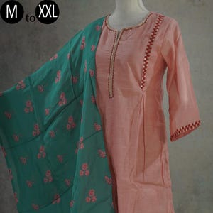 May include: A peach-coloured kurta with a green floral dupatta. The kurta has a round neckline and three-quarter sleeves with embroidered trim. The dupatta has a floral print and is made of sheer fabric. The kurta and dupatta are a traditional Indian outfit.