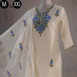 May include: Cream-coloured embroidered kurta suit with a matching dupatta. The suit has detailed blue floral embroidery on the neckline, sleeves, and hem. The dupatta features scattered floral motifs. Sizes available: M to XXL.