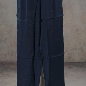 May include: Navy blue wide-leg pants with an elastic waistband. The pants are made of a lightweight, semi-sheer fabric. The pants are displayed on a white mannequin.