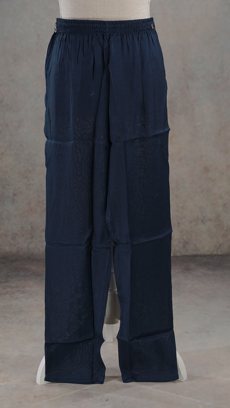 May include: Navy blue wide-leg pants with an elastic waistband. The pants are made of a lightweight, semi-sheer fabric. The pants are displayed on a white mannequin.