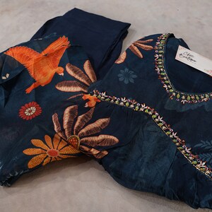 May include: A dark teal two-piece outfit with floral and bird patterns. The top has a beaded neckline and a tag that reads "Chic Boutique". The pants are a solid dark teal color.