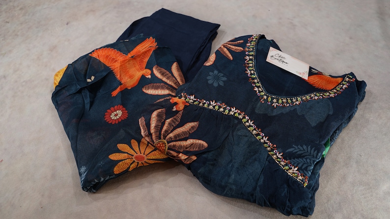May include: A dark teal two-piece outfit with floral and bird patterns. The top has a beaded neckline and a tag that reads "Chic Boutique". The pants are a solid dark teal color.