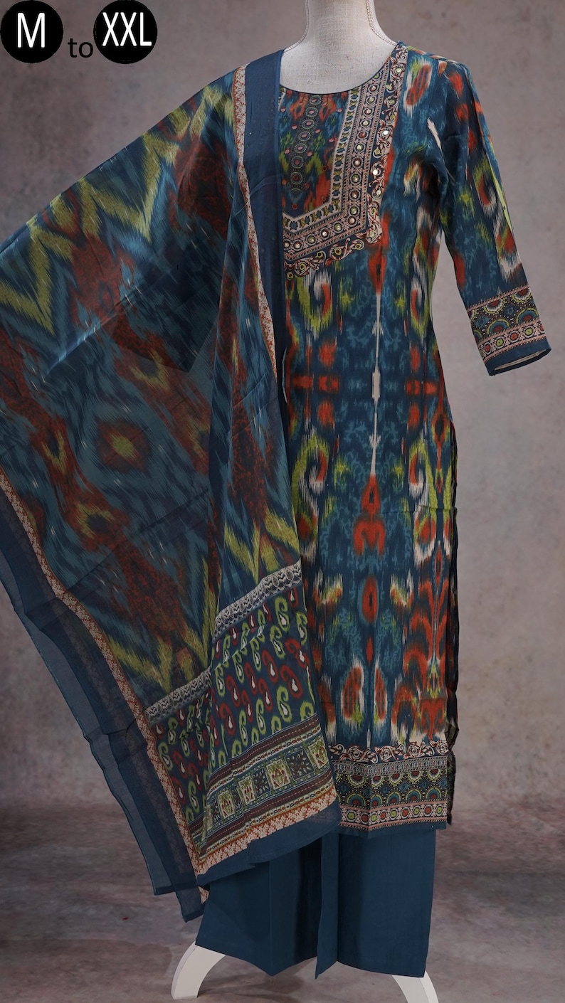 May include: A teal-colored salwar kameez set with a matching dupatta. The fabric features a colorful ikat pattern in shades of teal, red, yellow, and green. The neckline and sleeves are adorned with intricate embroidery and mirror work. Sizes available: M to XXL.