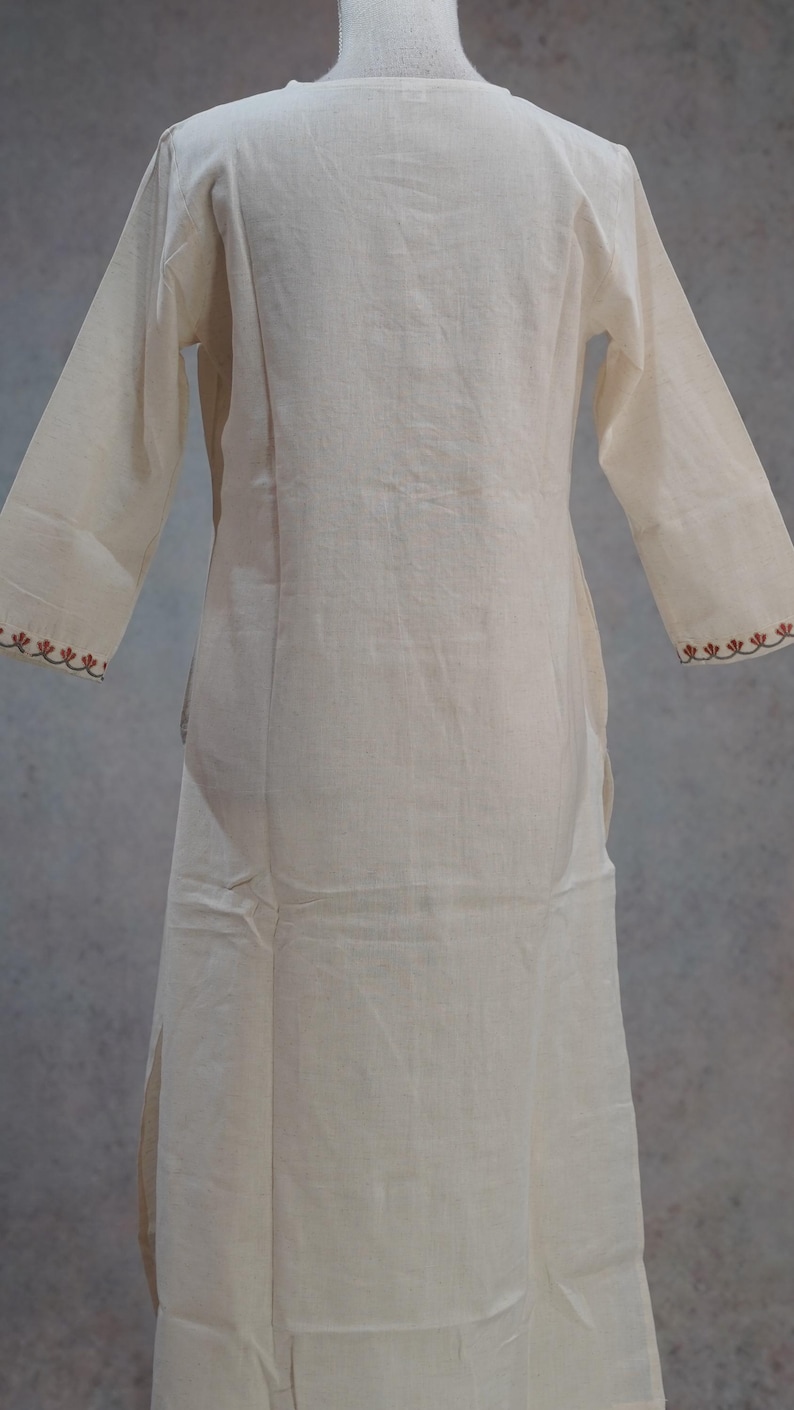 Puede incluir: Vestido t&uacute;nica color crema de manga larga. El vestido presenta un corte sencillo y relajado con cuello redondo y mangas largas. Los pu&ntilde;os est&aacute;n adornados con un patr&oacute;n bordado decorativo en color marr&oacute;n rojizo. La tela parece ligera.