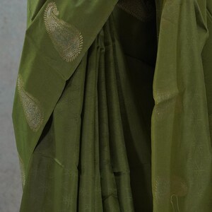 Puede incluir: Tela verde oliva con dise&ntilde;os de cachemira dorados. La tela est&aacute; drapeada, mostrando pliegues y textura. Los patrones de cachemira son detallados y se repiten en todo el material. El aspecto general es elegante y rico.