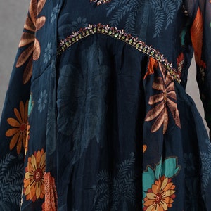 May include: A dark blue dress with a V-neckline, adorned with colorful floral and leaf patterns in orange, yellow, and green. The neckline is embellished with colorful beads. The dress is displayed on a mannequin.