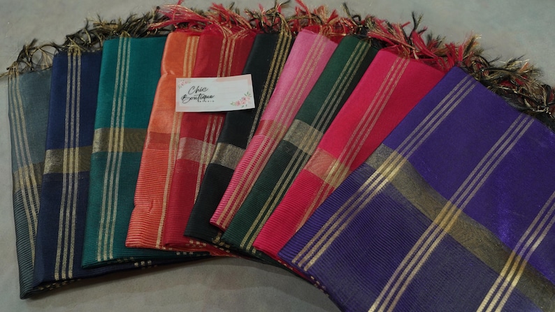 May include: A selection of vibrant scarves, each featuring gold stripes and fringed ends. The scarves are displayed in shades of blue, green, orange, red, pink, and purple. The label reads "Chic Boutique".