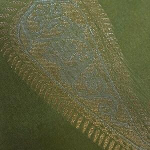 Puede incluir: Primer plano de un textil verde con un dise&ntilde;o de cachemira dorado y plateado. El intrincado patr&oacute;n est&aacute; detallado con elementos florales y curvos. La tela tiene un brillo sutil y el dise&ntilde;o est&aacute; centrado en el textil.