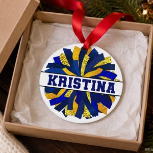 Cheer coach gift resting in a kraft box showing a purple and gold dance team photo keepsake and 2026 date.