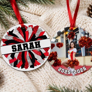 Custom cheerleader ornament 2026 in red and black resting on a cozy knit sweater showing a full team photo side.