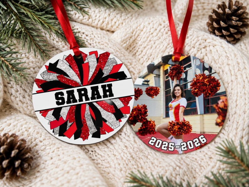 Custom cheerleader ornament 2026 in red and black resting on a cozy knit sweater showing a full team photo side.