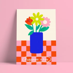Peut inclure: Une affiche colorée représentant un vase bleu avec des fleurs rouges, jaunes et roses. Le vase est posé sur un fond à carreaux orange et rose, avec l'inscription "happiness is here" dans un ovale blanc.