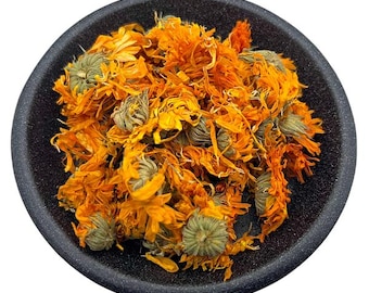 Può includere: Una ciotola di petali di calendula secchi di colore arancione e giallo. I petali sono sciolti e sparsi nella ciotola.