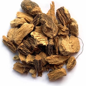 May include: Close-up of a pile of dried, light brown and dark brown, irregularly shaped pieces. The pieces have a rough, textured appearance, with visible ridges and crevices. The background is plain white.