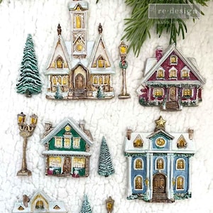 May include: A collection of miniature Christmas village houses and trees in various colors, including white, red, green, and blue. The houses feature intricate details and are decorated with snow. Includes street lamps.