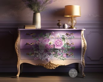 May include: A purple and gold dresser with three drawers decorated with a floral design. The dresser has ornate gold accents and sits on a wooden floor. A bouquet of lavender is in a vase on top of the dresser.
