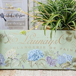 May include: A green wooden box with a floral design and the text "Launay & C Boulangerie de Pain". The box is decorated with hydrangeas, leaves, and vines.