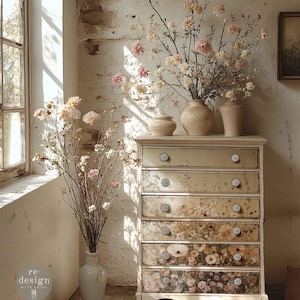 May include: A vintage-style chest of drawers with floral designs on the drawer fronts. The chest is cream-colored with ornate knobs. The room is decorated with vases of flowers and branches, creating a soft, natural aesthetic.