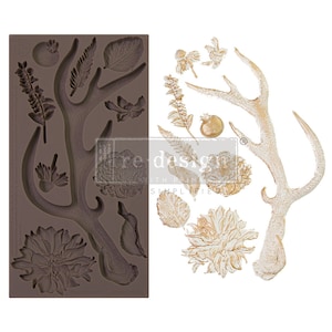 May include: A brown silicone mold with various botanical designs, including flowers, leaves, and antlers. Next to it are several gold-colored decorative elements, such as a deer antler and floral accents, perfect for crafting and DIY projects.