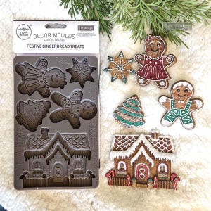 May include: A gingerbread house, a Christmas tree, a snowflake, a gingerbread person, and an angel are shown in a silicone mold for baking gingerbread cookies. The mold is labeled "Decor Moulds Festive Gingerbread Treats".