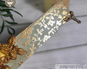May include: A rectangular wooden bookmark featuring a sage green base with a metallic gold floral pattern. The bookmark is adorned with a three-dimensional gold leaf embellishment at the bottom and a small bronze-toned metal angel figure at the top.