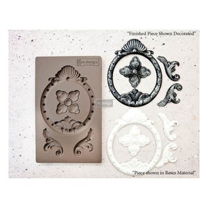 May include: A silicone mold for creating decorative resin pieces. The mold features a circular design with a floral center and two scroll designs. The mold is shown with two finished resin pieces, one in silver and one in white.