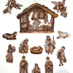 May include: A detailed nativity scene set with figures of angels, the Holy Family, the Three Wise Men, and animals. The figures are in shades of brown, beige, and gold, with a rustic stable backdrop and a star. The set is designed for Christmas decor.