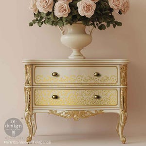 May include: A cream-colored two-drawer nightstand with gold accents and floral detailing. The drawers feature a yellow floral pattern and brass knobs. A vase of pink roses sits atop the nightstand. The text "#676155 vineyard elegance" is visible.