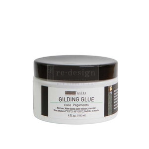 May include: A white jar of "Gilding Glue" with a black lid. The label includes the text "re-design" and "Kacha". The jar contains 4 fl. oz. (118.3 ml) of non-toxic, water-based, water-resistant glue that dries clear.