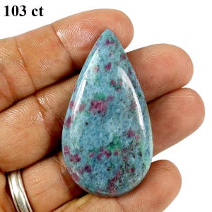 May include: A pear-shaped polished gemstone weighing 103 ct, featuring a mottled blue and green base colour with embedded deep pink and magenta inclusions throughout the surface, presented in a smooth, cabochon-style cut with a pointed top.