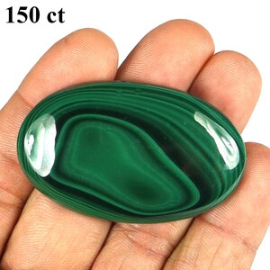 May include: Oval-shaped malachite gemstone with a polished, glossy surface. The gemstone features a deep green color with swirling patterns and a white area. The text "150 ct" is in the upper left corner.
