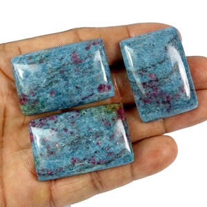 May include: Three rectangular polished gemstones featuring a vibrant blue base color with scattered deep pink and magenta inclusions throughout the surface. Each stone has a smooth, glossy finish and a flat, cabochon-style top surface.